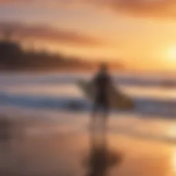 Surfer carrying a surfboard on a beach at sunset.