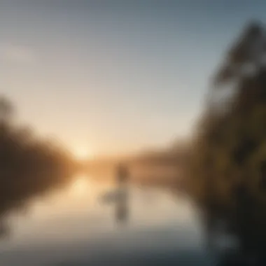 A serene lake reflecting the sunrise with a paddleboarder gliding across the water